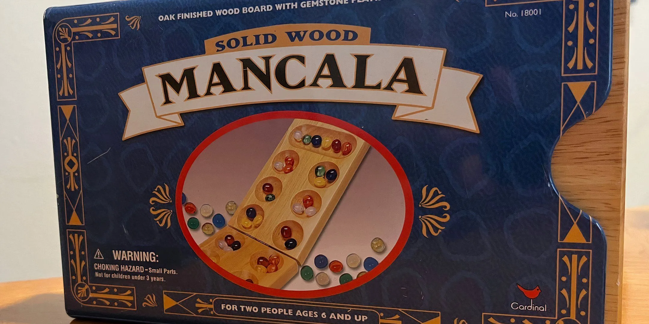 Bìa hộp board game Mancala với những viên đá màu sắc, thể hiện sự đơn giản nhưng ẩn chứa chiến thuật tính toán trong trò chơi cổ xưa này.