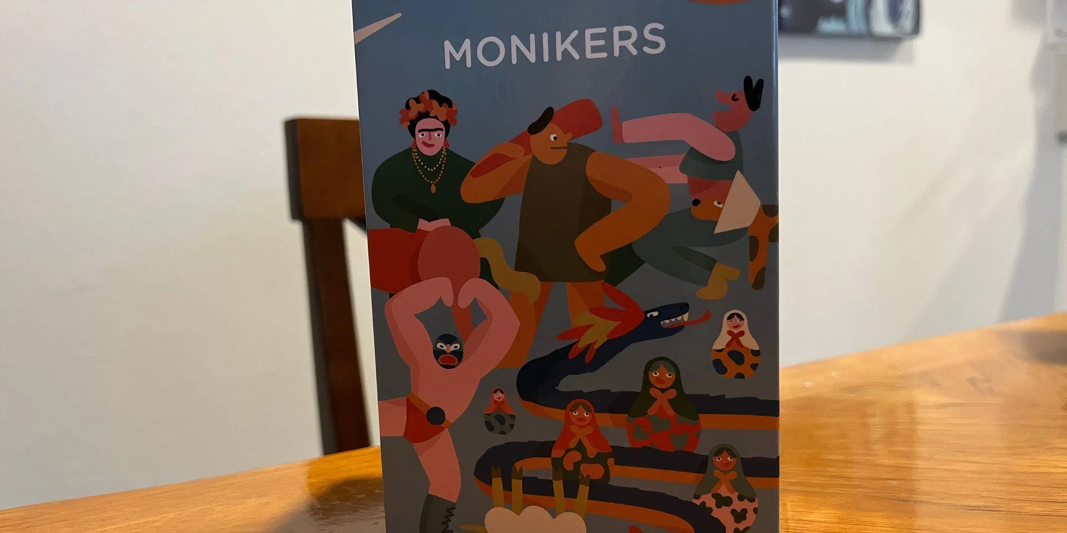Bìa hộp trò chơi Monikers, một biến thể hiện đại của trò đố chữ và diễn tả, được yêu thích trong các nhóm bạn nhưng ít khi được chơi trọn vẹn theo luật.