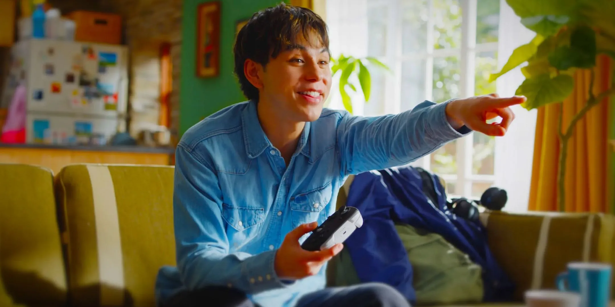 Game thủ đang chơi Nintendo Switch 2 và sử dụng tay cầm Pro Controller màu trắng, chỉ tay vào màn hình.
