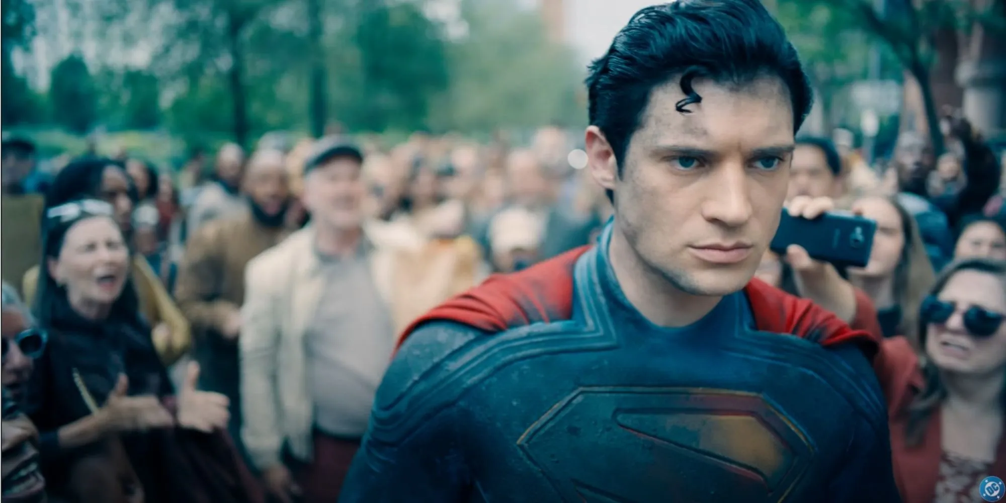 Superman đứng trong cảnh đổ nát, trông có vẻ thất vọng khi đám đông phía sau la ó.